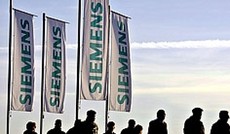  APA/Matthias Schrader, Menschen bewegen sich vor Siemens-Flaggen