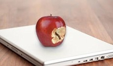  Fotolia/James Steidl, cschirra (Montage), Apple Notebook auf dem ein angebissener Apfel mit Wurm liegt.